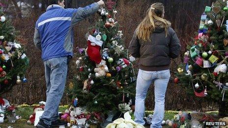 People placing an angel on top of a Christmas tree at a makeshift memorial in Newtown, Connecticut, 18 December