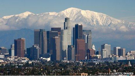 The skyscrapers of Los Angeles climb into a skyline dominated by the snow-covered San Gabriel mountains