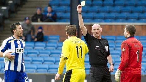 Paul Cairney is booked by Bobby Madden