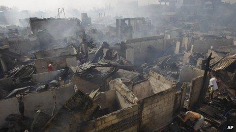 A resident drinks from a broken hose as others salvage belongings after a fire hit a slum area in suburban San Juan, east of Manila, 25/12/12