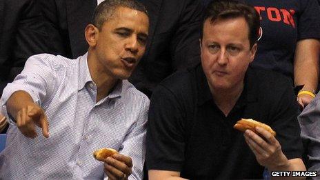 US President Barack Obama and British Prime Minister David Cameron eat hot dogs at a basketball match