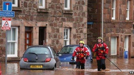 Firemen walk through floodwater on the High Street in Stonehaven