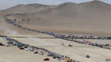 Hundreds of cars line the desert sands watching the competitors in the Dakar rally