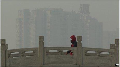 A man wearing a mask walks over a bridge in smoggy Beijing (14 Jan 2013)