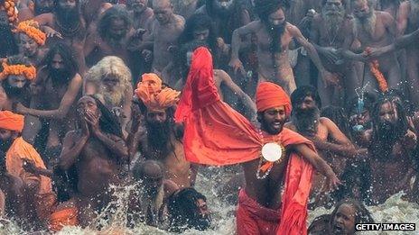 Naga sadhus run in to bathe in the waters of the holy Ganges river during the auspicious bathing day of Makar Sankranti of the Maha Kumbh Mela on 14 January 2013