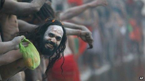 A Naked Hindu holy man or a Naga Sadhu watches others as they wait for a dip at Sangam