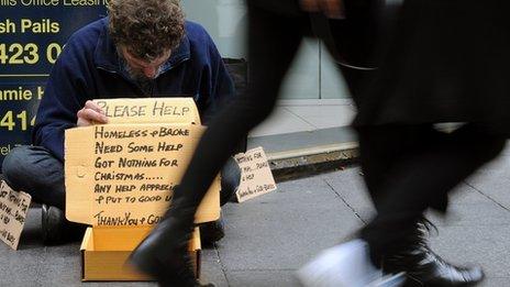 Shoppers walk past a homeless man