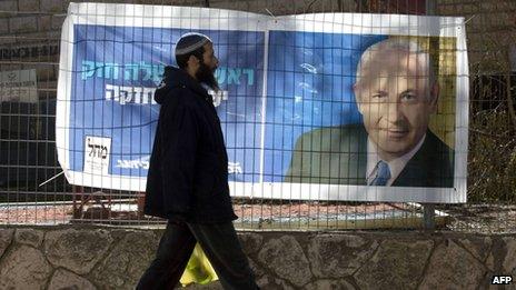 Man walks past election poster of Benjamin Netanyahu, in Kiryat Arba settlement (15/01/13)