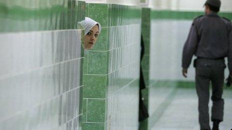 File picture of female inmate peering from behind a wall as a guard walks past in the female section of Evin prison (June 2006)