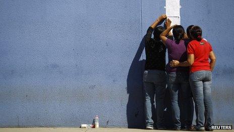 Women check the list of those killed in a prison riot at Uribana jail.