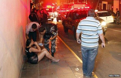 A survivor is helped by emergency workers near the Kiss club in Santa Maria, Brazil, 27 January