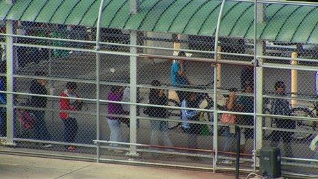 People walk around behind a metal fence in Laredo, Texas