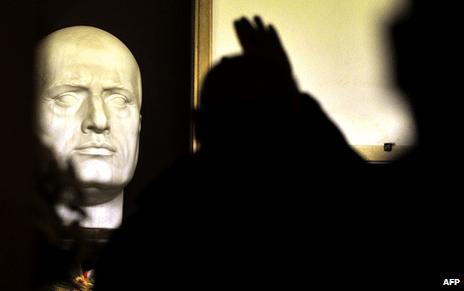 An admirer salutes the bust of Mussolini on his tomb in Predappio, Italy, 28 October 2012