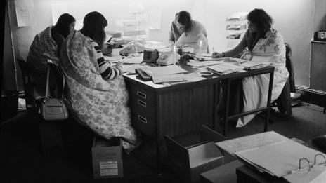 Four women working wrapped in quilts to keep warm in 1974