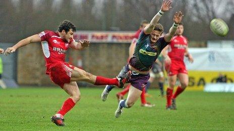 Hallam Amos of Dragons charges down a kick by Ryan Davis of London Welsh