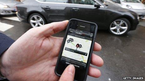 A person poses using a smartphone to hire a chauffered car