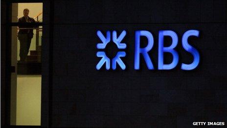 RBS employee looks out from the headquarters building next to a neon sign