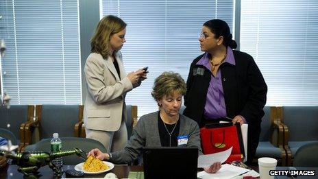 Office worker eating while colleagues talk behind her