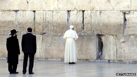 Pope Benedict praying at the Western Wall in Jerusalem as two Israeli men look on, 12 May 2009