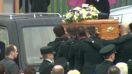 Pall bearers carry coffin behind hearse