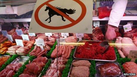 A butcher works behind a "no horsemeat" sign at Bates Butchers in Market Harborough, central England