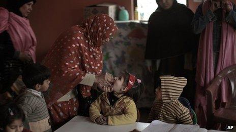 Pakistani health workers gives a polio vaccine to child, at a kindergarten in Islamabad, Pakistan on 30 January