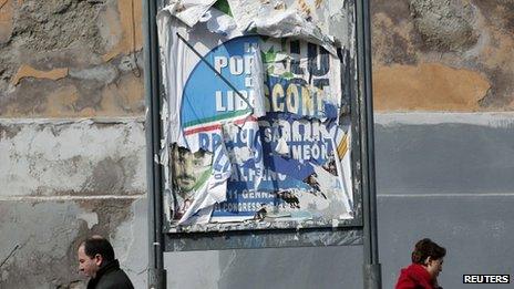 People walk next to ripped electoral posters in Rome. Photo: February 2013