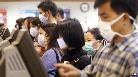 Unemployed people wearing masks look for jobs at a job centre in Hong Kong to protect against a killer outbreak of pneumonia 15 April 2003.