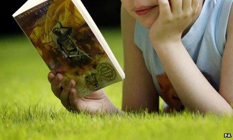 Child reading Narnia book on grass