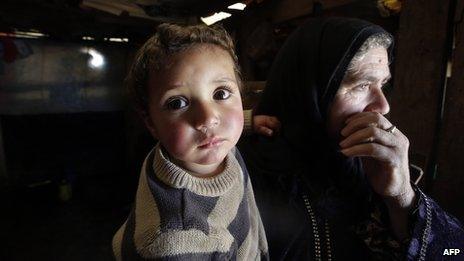 A Syrian woman carries her two-year-old grandson Mohammed at a refugee camp in the Bekaa valley in Lebanon