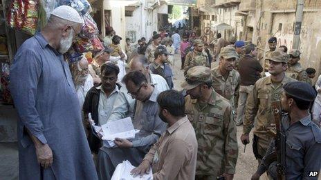 Pakistani soldiers stand guard as staff members of the election commission verify lists of voters in Karachi