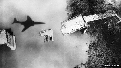 A US jet flies over a destroyed bridge in North Vietnam