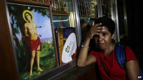 A woman rests against a wall as she listens to a radio announcement of the new Pope aired inside the Cathedral in Rio de Janeiro
