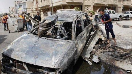 A boy inspects a car destroyed by a bomb blast near the Green Zone in Baghdad (19 March 2013)
