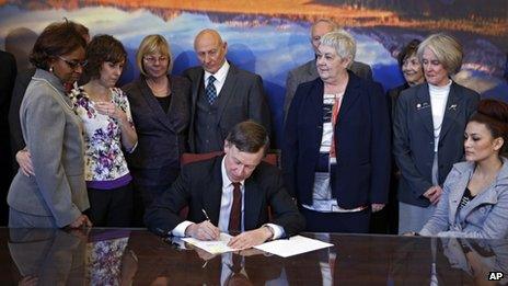 Sponsors and family members of victims watch as Colorado Governor John Hickenlooper signs the bills into law in Denver on on 20 March 2013.