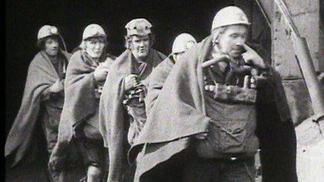 Men wearing hard hats walking out of a mine