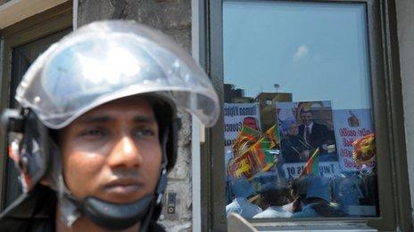 Pro-government activists are reflected in the glass of the US embassy during a protest in Colombo on March 21, 2013,