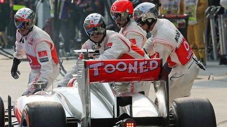 Jenson Button is pushed back into the pitbox