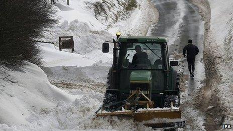 A runner makes his way up a cleared road flanked by deep snow in Burnley, Lancashire, on 25 March 2013