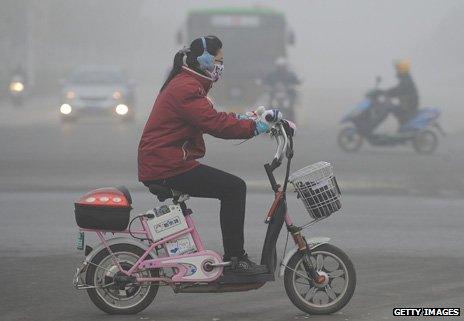 Woman on an electric bike in the smog in Beijing