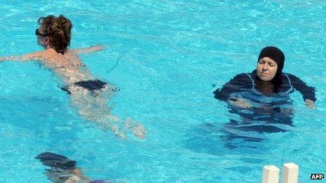 women swimming in tunisia - one in a bikini, the other covered up