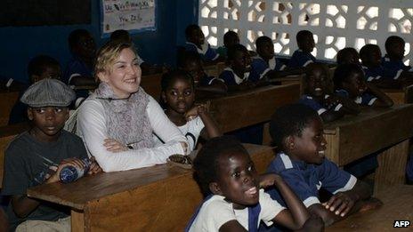 US pop star Madonna (2nd L) sits on April 2, 2013 with the two children she adopted in Malawi, David Banda (L) and Mercy James (3rd R), in a classroom at the Nkoko Primary School