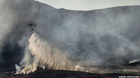 Helicopter releases water over hill fire