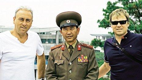 Nigel Green and his cousin Andrew Drury pose with a North Korean guard