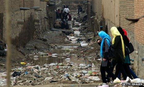 Women walk past heroin addicts