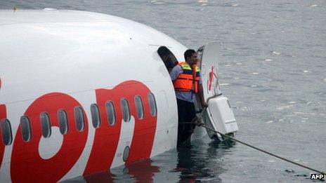 A man stands in the cabin door of the crashed plane near Denpasar airport, Bali, 13 April