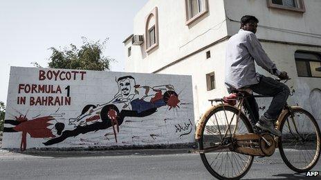 A foreign worker cycles past graffiti against holding the upcoming Formula 1 Grand Prix in Bahrain in the village of Barbar, west of the capital Manama, on March 31, 2013