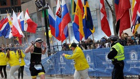 Police and runners react to an explosion during the Boston Marathon