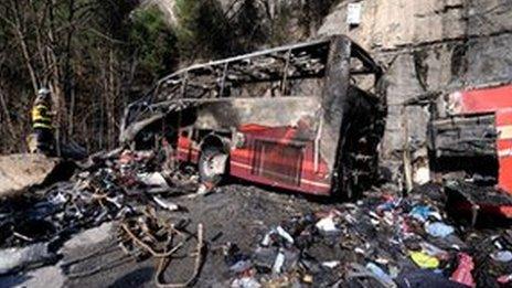 Firefighter stands near bus wreckage