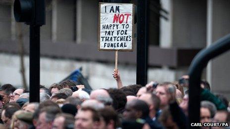 A member of the crowd holds up a sign